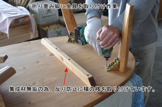 折り畳み脚に金具を取り付け作業。集成材無垢の為、反り防止に横の桟を取り付けています。